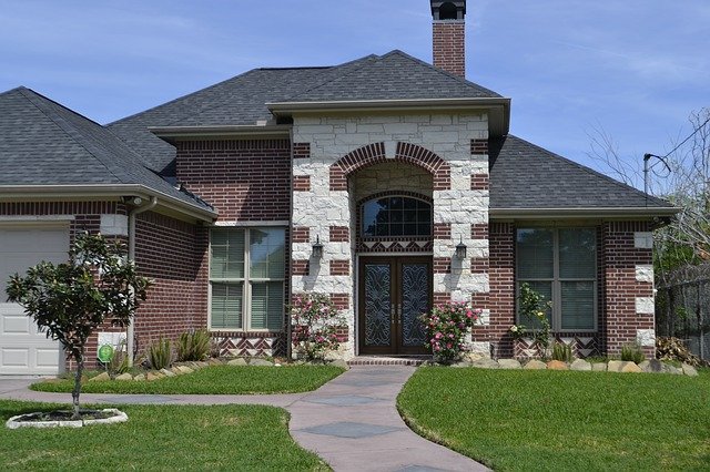 ​​A brick and white stone house with a green lawn